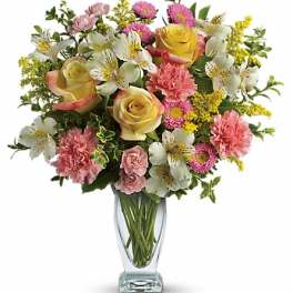 Bouquet of yellow roses, pink carnations, and white alstroemeria in a clear glass vase