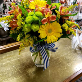 Bouquet of yellow gerbera daisies and orange alstroemeria in a glass vase