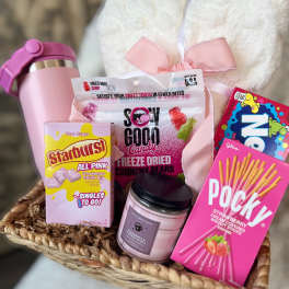 Gift basket with candy, a candle, and a pink tumbler