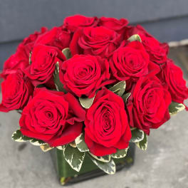 Bouquet of red roses with variegated leaves in a glass vase