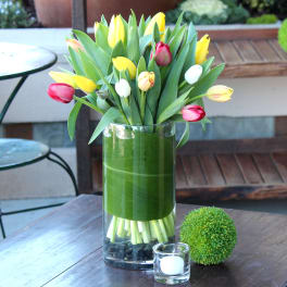 Tulip bouquet in a clear glass vase with a green wrap