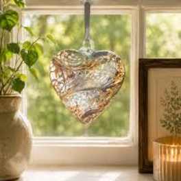 Heart-shaped glass ornament hanging in a sunlit window