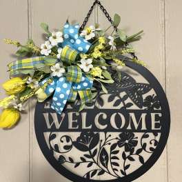 Floral welcome sign with yellow and white flowers and blue ribbons