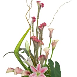 Pink lilies and calla lilies arranged in a cream vase