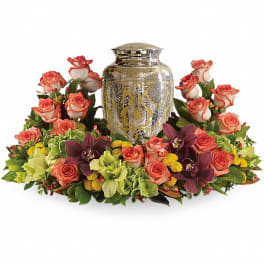 Coral roses arranged around a silver urn centerpiece