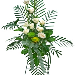 Tall standing floral spray with white roses and tropical greenery on an easel