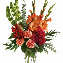 Orange gladiolus and red roses in a clear glass vase
