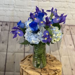 Blue roses and purple irises in a glass vase
