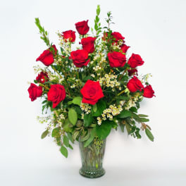 Red roses arranged in a clear glass vase with small white filler flowers