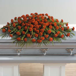 Red carnation casket spray with greenery on a gray casket