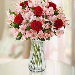 Red roses and pink lilies arranged in a clear glass vase.
