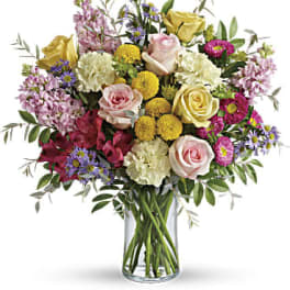 Mixed bouquet of roses, carnations, and daisies in a glass vase