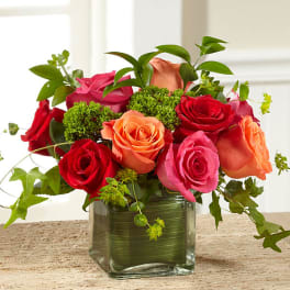 Mixed roses in a square glass vase with greenery