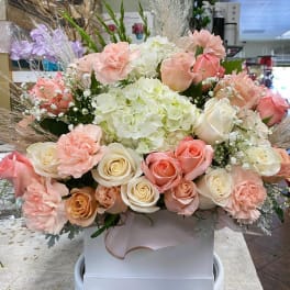 Pastel bouquet of roses, carnations, and hydrangeas in a white box