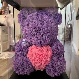 Purple and pink teddy bear made of roses inside a clear display box