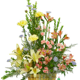 Tall mixed flower arrangement in a gold basket with lilies and pink blooms