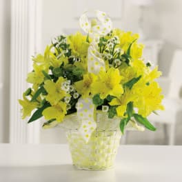 Yellow flowers in a woven basket with a white polka-dot ribbon