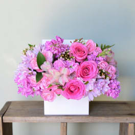 Pink and lavender flower arrangement in a white box