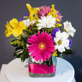Mixed bouquet with pink, white, yellow, and purple flowers in a glass vase