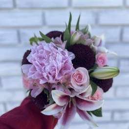 Handheld bouquet of pink and white flowers with dark purple blooms