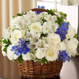 White roses and blue flowers arranged in a wicker basket