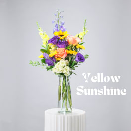 Mixed bouquet in a glass vase with sunflowers, roses, and purple blooms