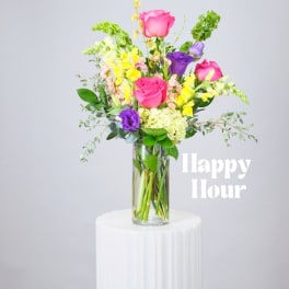 Mixed bouquet of pink, purple, and yellow flowers in a clear glass vase