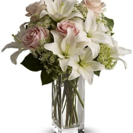White lilies and pale pink roses in a clear glass vase