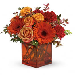 Orange and red flowers in a square glass vase