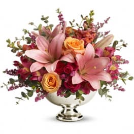 Pink lilies and roses arranged in a silver pedestal bowl