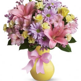 Pink and lavender bouquet in a yellow vase with a pink ribbon