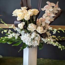 White roses and orchids arranged in a tall white vase