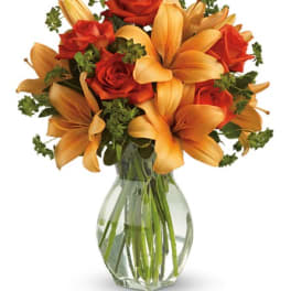 Orange lilies and red roses in a clear glass vase