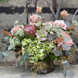 Mixed bouquet of pink and green flowers in a low vase