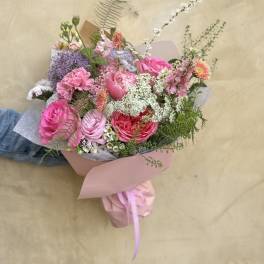 Hand-tied bouquet of pink and purple flowers wrapped in paper