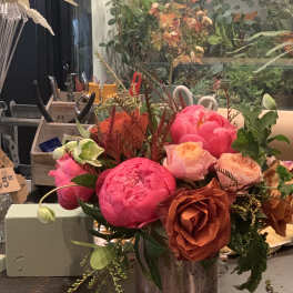 Bright pink and peach peonies and roses in a metal vase