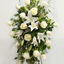 Tall white floral standing spray with roses and lilies on a metal easel