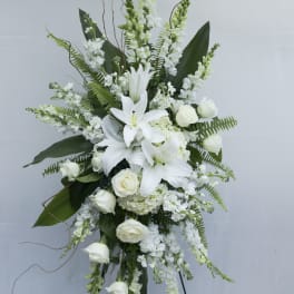 White lilies and roses in a tall standing floral arrangement