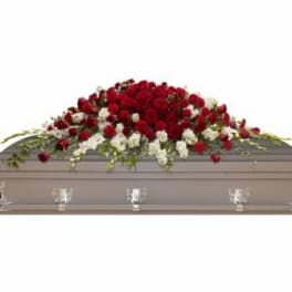 Red and white floral casket spray on a gray casket