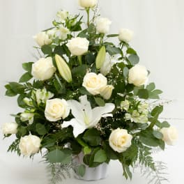 White roses and lilies arranged in a white vase