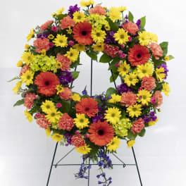 Colorful floral wreath on a metal stand with yellow, orange, purple, and pink blooms
