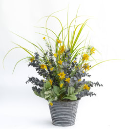 Yellow flowers and tall grass in a gray metal pot