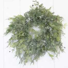 A green foliage wreath with frosted accents on a white door