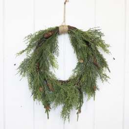 Evergreen wreath with pinecones hanging on a white door