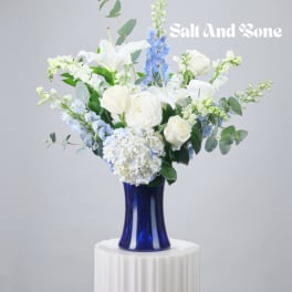 White and blue floral arrangement in a cobalt vase