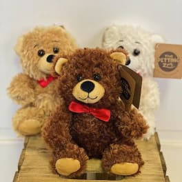 Three teddy bears with red bows on a wooden crate