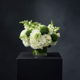 White and green floral arrangement in a glass vase
