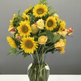 Sunflower and yellow rose bouquet in a clear glass vase