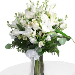 White floral bouquet in a glass vase with a sheer ribbon