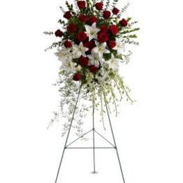 Standing floral spray with red roses and white lilies on an easel